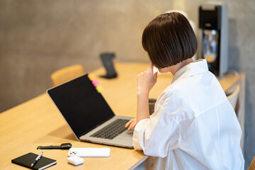 自宅の部屋でノートPCを操作する若い女性
