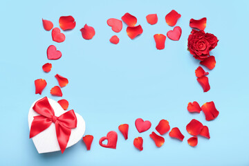 Frame made of gift box for Valentine's Day and rose petals on blue background