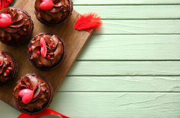 Board with tasty chocolate cupcakes for Valentine's day on color wooden background