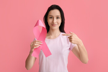 Young woman with ribbon on pink background. Breast cancer awareness concept