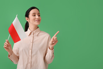 Beautiful young woman with flag of Poland pointing at something on color background
