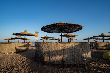 Fototapeta na wymiar Seascape -view of palm trees, resort beach with sun loungers, umbrellas and the sea. Egypt.