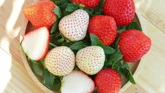 Fresh strawberries in a wooden basket on wooden background, Red Strawberries and white strawberries Pine berry or Hula strawberry in Bamboo basket.