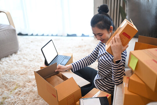 Smiling young woman online seller preparing parcel box of product for delivery to customer.