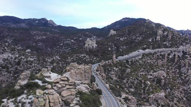 The Catalina Highway Scenic Drive winds through rock hoodoos on its way to the top of Mount Lemmon in Tucson, Arizona. The roadway is empty as the camera flies forward overhead.