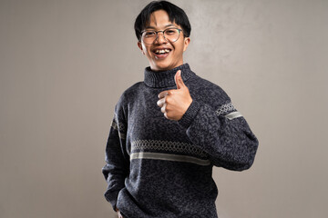 Fototapeta premium Smiling man in sweater and sunglasses gesturing with tumbs up