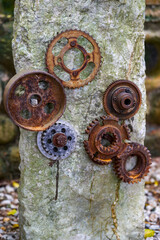 A stone in the park is inlaid with a pile of rusty gear sculptures