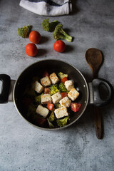 Paneer or cottage cheese cubes along with vegetable salad in a cooking pan. 