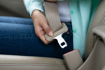 Close up hands woman sitting on car seat and fastening seat belt car. Female hand sitting inside car fastening seat belt. Safe driving while driving, safety first concept.