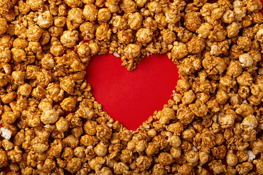 love concept image of heart shape frame made of caramel popcorn on red background