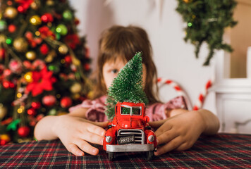 Little girl playing with toy truck in christmas holidays. Christmas mood. Selective focus.