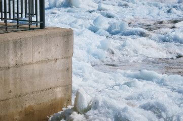 Part of the city embankment made of concrete with a fence. Background from shards of ice. Ice...