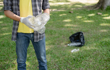 Man's hands pick up plastic bottles, put garbage in black garbage bags to clean up at parks, avoid...