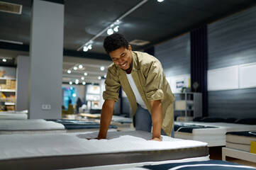 Man choosing bed checking orthopedic mattress softness