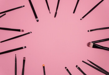 Set of makeup brushes on pink background.