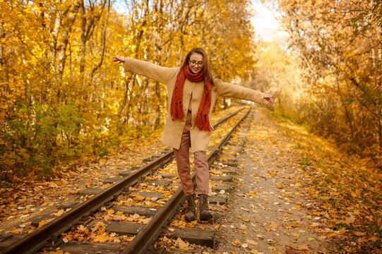 Woman balancing on railway over autumn background