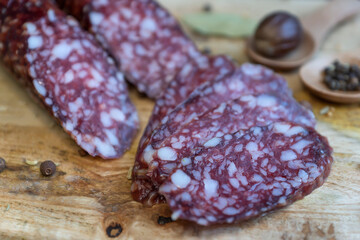 Smoked sausage and various spices on a wooden cutting board.