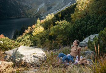 Naklejka premium Young woman on a hiking trip sitting on a rock