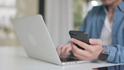 Close Up of Male Hand with Laptop using Smartphone