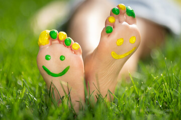 Fototapeta Happy child with smile on feet lying on green spring grass obraz