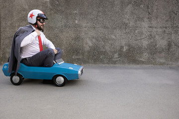 Funny businessman driving retro pedal car outdoor