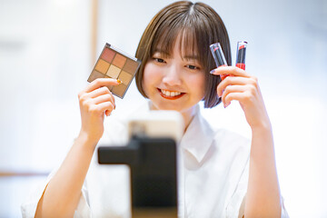 スマートフォンを使ってコスメグッズを紹介する女性