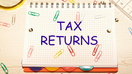 tax return text on a notebook in a cage with scattered paper clips on a notebook and a table