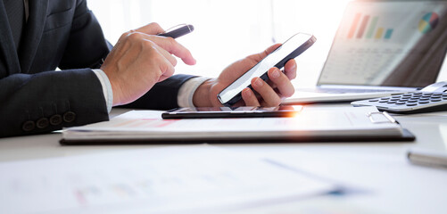 Businessman working at office with document, doing planning analyzing the financial report, business plan investment, finance analysis concept.Using smartphone and tablet.