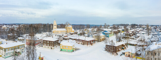 Fototapeta na wymiar Panorama of a small city in the depths of Russia from a height. Orthodox churches and traditional old wooden houses, Kologriv in the Kostroma region and a winter view of the city