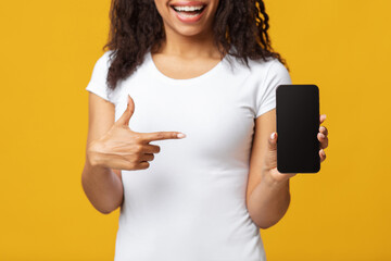 Black woman pointing at smartphone with black screen, cropped, mockup for your website or design