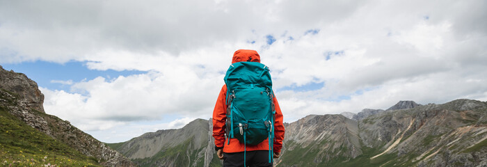 Woman backpacker hiking on alpine mountain peak