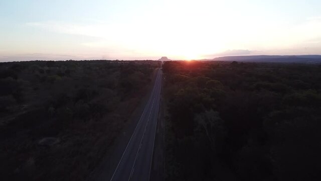Aerial view of one car cruising fast on Trans-Amazonian highway during sunset in the state of Maranhão, Brazil