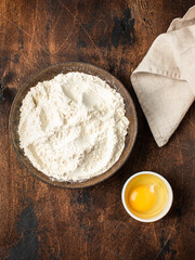 Bowl with wheat flour on a wooden background.  Egg.  Ingredients for the dough.  Rustic style.