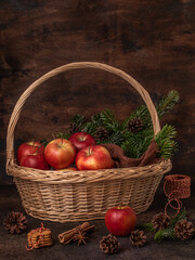 Christmas still life. Red apples in a basket. Cinnamon, spruce branches, gingerbread cookies.