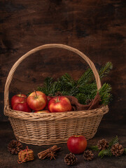 Christmas still life. Red apples in a basket. Cinnamon, spruce branches, gingerbread cookies.