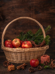 Christmas still life. Red apples in a basket. Cinnamon, spruce branches, gingerbread cookies.