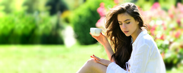Naklejka premium Spring time. Woman in summer field with coffee. Happy girl outdoors in rose garden. Woman enjoy outdoor recreation. Natural beauty. Spring design for banner or website header, copy space.
