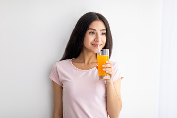 Happy Indian woman holding glass of fruit juice, having refreshing drink at home. Detox, weight loss, dieting concept