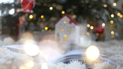 Christmas book mystically turns pages against background of Christmas decorations with tree garlands, balls and bokeh lights. Christmas, New Year. Christmas miracle, mysticism.