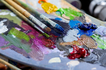 Tubes of oil paint, palette and artist paintbrushes closeup