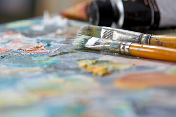 Tubes of oil paint, palette and artist paintbrushes closeup