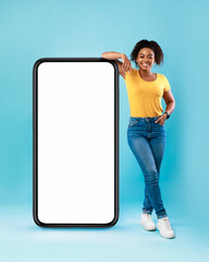 Mobile app ad. Black woman leaning on huge smartphone with empty screen, advertising new website or application, mockup
