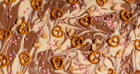 Weiße und braune Schokolade vorbereitet für eine Bruchschokolade dekoriert mit Brezel, Zucker Perlen und Nüssen
