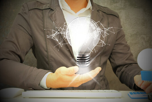 Hand stroking a light bulb on a wood block with Word Ideas, fresh idea concept with innovation and inspiration, revolutionary science and communication concept