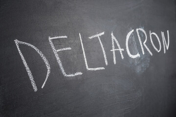 Obraz premium The Deltacron is a new combination version of the Delta variant and the Omicron variant written in chalk on a black board. COVID-19 Deltacron Variant Concept.