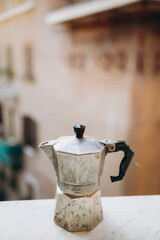 old steel Italian geyser coffee maker on a marble windowsill. moka pot closeup. coffee prepared in...