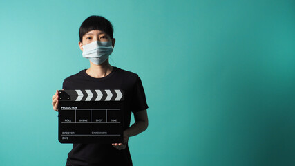 Asian woman wear face mask and hand's hold black clapper board or movie slate use in video...