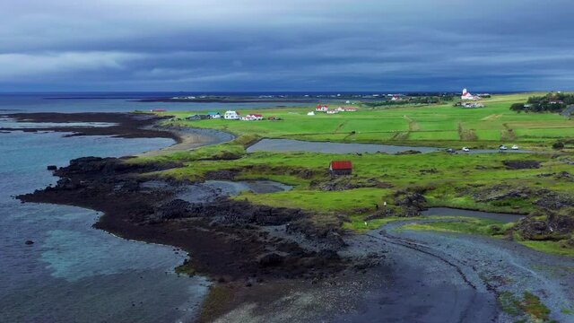Aerial View Of Volcanic Coastline With Green Fields And Houses In Gardakirkjugardur, Gardabaer, Iceland.