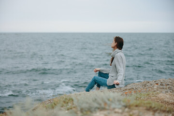 Naklejka na ściany i meble pretty woman seated on the coast sweater landscape Relaxation concept