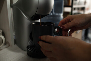 Coffee machine pouring coffee into a cup with female hands